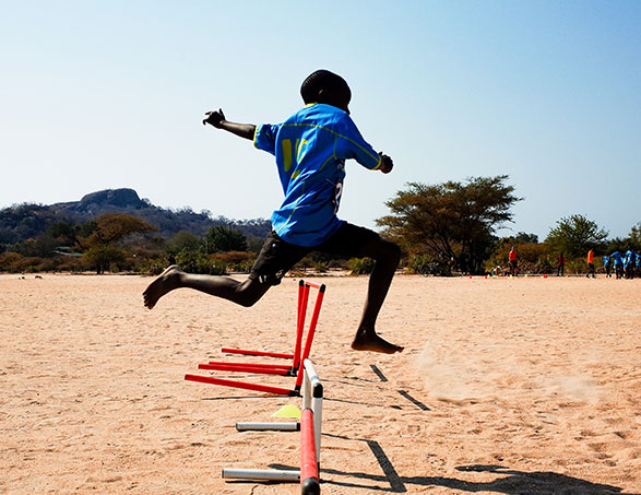 Sport and education in Malawi with a boy jumping hurdles